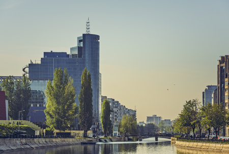 Bucharest, Romania - April 14, 2014: Sunrise city view with modern high-rise glass office building on the bank of Dambovita river in central district of Bucharest.のeditorial素材