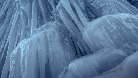 Frozen waterfall stream. Vertical slippery steep ice wall with long icicles.の写真素材
