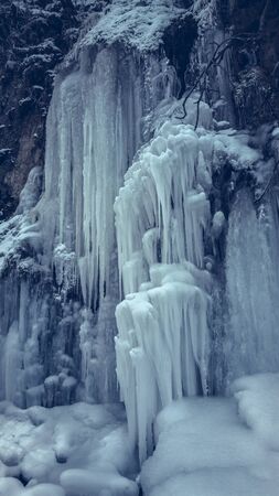 Frozen waterfall stream with long icicles.