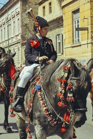 Brasov, Romania - April 27, 2014: Young boy in traditional costume rides adorned stallion during the Junii Brasovului (Youths of Brasov) festival.のeditorial素材
