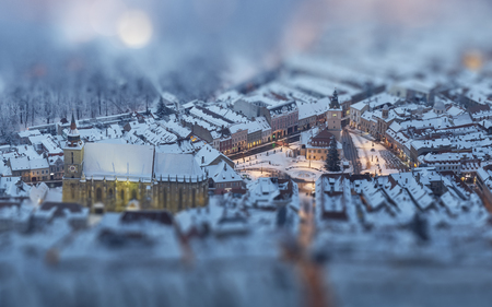 Aerial twilight cityscape of the snowy Council Square in the historic center of Brasov city, Romania. Tilt-shift blur effect.の写真素材