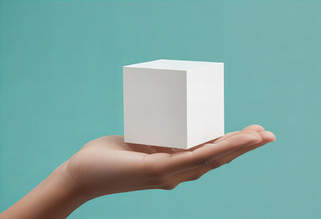 A minimalist image of a hand gently holding a plain white cube against a light teal background, conveying simplicity and elegance.の素材