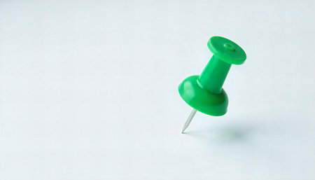 A minimalist image featuring green push pins scattered on a white background. The closest pin is sharply in focus, with others softly blurred in the background. The bright green color stands out against the stark white, creating a simple yet visually appealing contrast. This image represents organization and attention to detail in an office or home workspace.Aspect Ratio: 16:9の素材