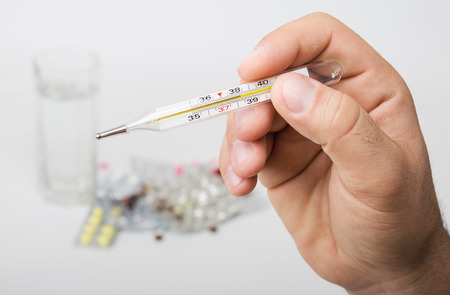 man holding a thermometer in hand looking at result of the test body temperature