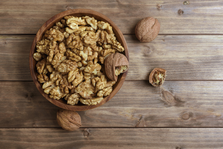 Walnuts in wooden bowl on wooden tableの写真素材
