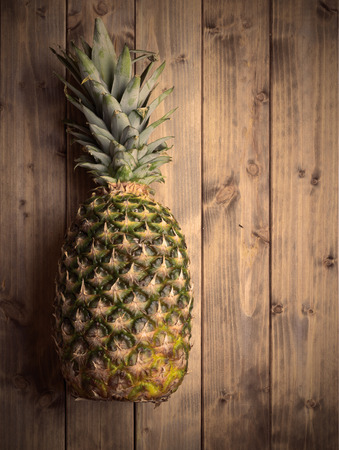 whole pineapple on a wooden table. Photo in vintage styleの写真素材