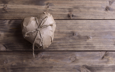 Heart wrapped in brown kraft paper, on wooden backgroundの写真素材