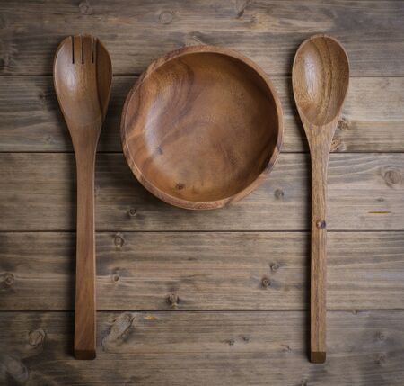 Cutlery made of wood, a spoon, a fork and a bowl on the tableの写真素材