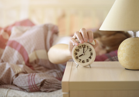girl turns off the alarm clock waking up in the morning from a callの写真素材