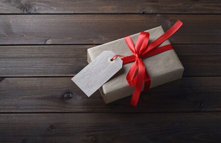 gift box with red ribbon and with a price tag on wooden table