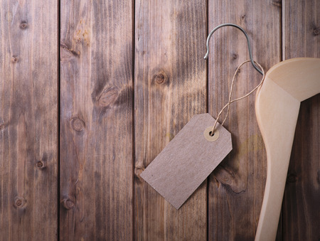 coat hanger with blank tag on background of wooden planksの写真素材