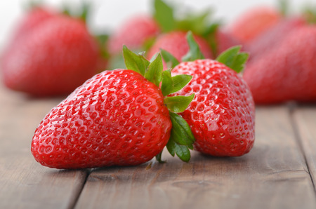 two strawberries closeup on the foreground and on blurred background heap of strawberriesの写真素材