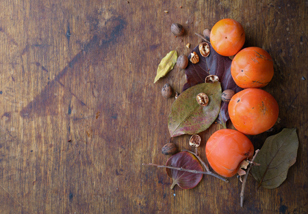 ripe persimmon with pecans on the old wooden backgroundの写真素材