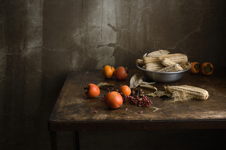 still life with fruit and corn in an aluminum bowl on a wooden old tableの写真素材