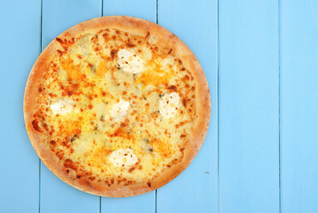 Baked pizza with four kinds of cheese on a wooden backgroundの写真素材