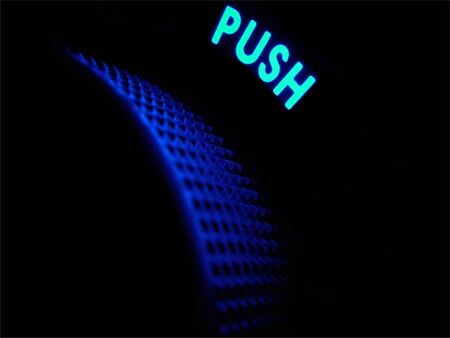 Neon word push glows in a dark blue haze above a power and volume handle.の写真素材