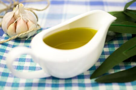 Olive oil in a gravy boat with garlic and olive leaves