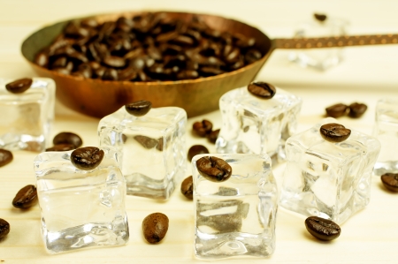 Pieces of ice with coffee beans. Background of coffee beans roasted in a pan.の写真素材