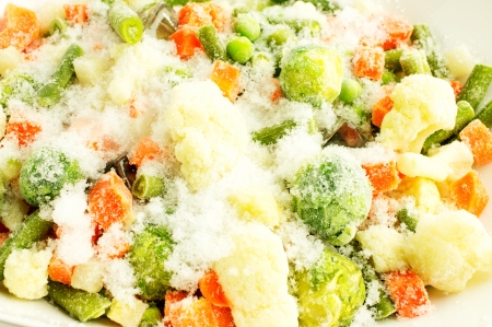 Mixture of frozen vegetables, carrots, peas, broccoli, green beans, Brussels sprouts, cauliflower in white bowl with ice and snow. For background.の写真素材