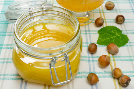 Honey in a glass jar on a checkered tablecloth.の写真素材