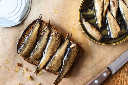 Sandwich with sprats on a table with a can of sprats