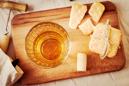 White wine in a glass on the table with crackersの写真素材