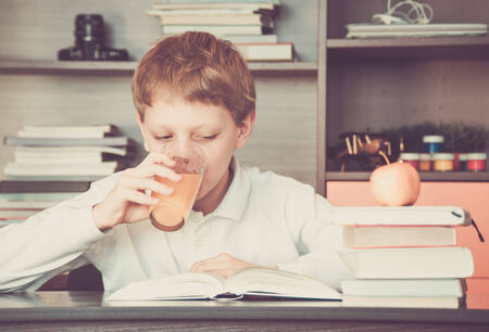 Boy reading a book and orange juice on the tableの写真素材
