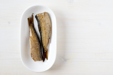 Smoked sardines in a white plate top view