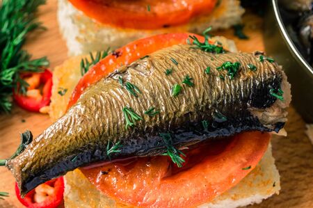 Toasts with a large smoked sardines. On the table hot peppers and olivesの写真素材