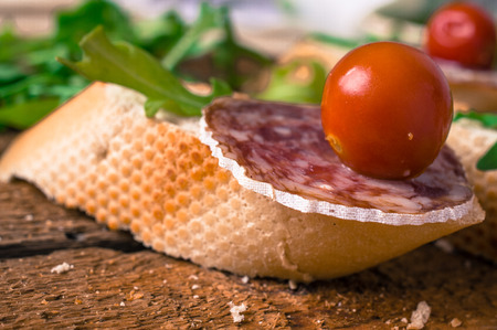 Spanish appetizer tapas, pintxos, pincho with arugula, cherry tomatoes and sausageの写真素材