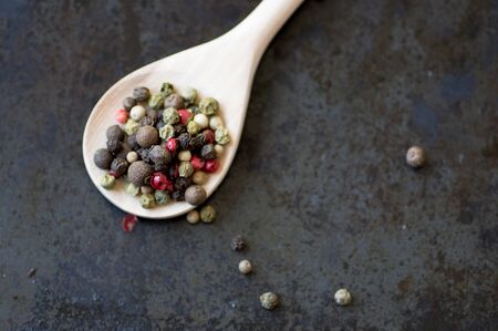 Mixture of different peppercorns in a wooden spoon top viewの写真素材