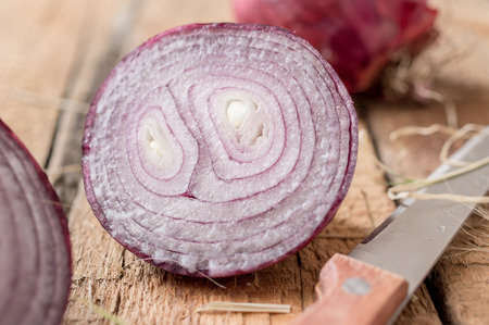Half red onion on a wooden board close knifeの写真素材