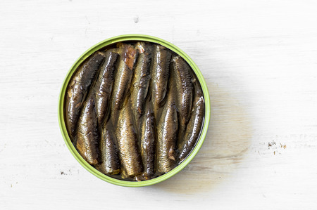 Tin with smoked sardines on a white wooden table top view.の写真素材