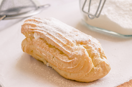 Eclair custard in powdered sugar on the tableの写真素材