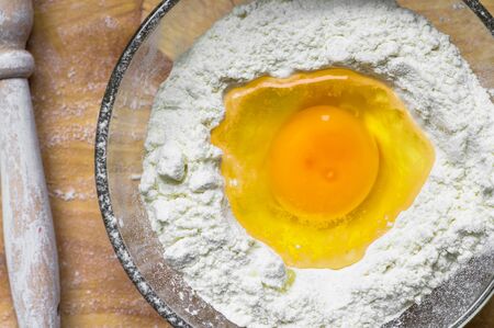 Cooking dough for pasta in a bowl with the egg and flour a top view