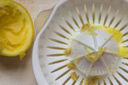 Squeezed lemon next to the juicer top viewの写真素材