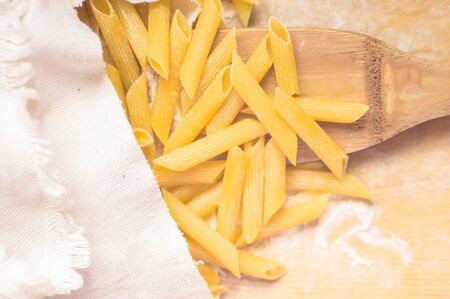 Dry pasta on a wooden scoop in sackの写真素材