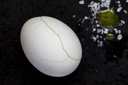 Egg with cracked shell on a black backgroundの写真素材