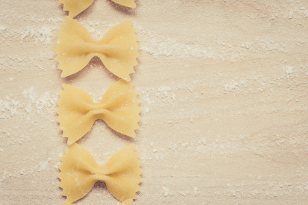 Farfalle pasta on the wooden background with flourの写真素材