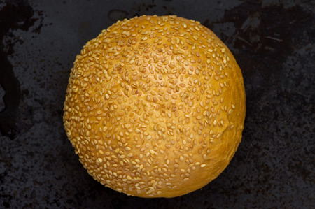 Bun with sesame seeds on a black background top view