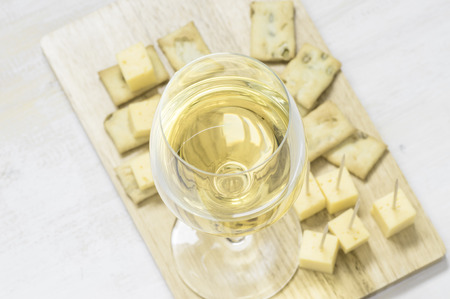Wineglass of white wine on a wooden board with appetizersの写真素材