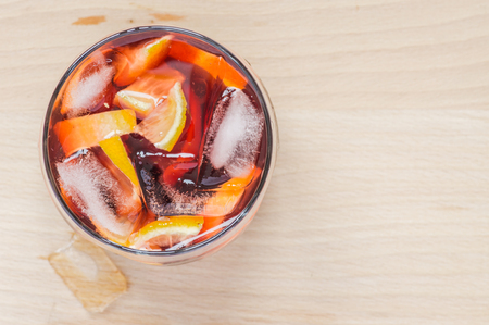 Sangria wine in the wineglass and pieces of ice on wooden tableの写真素材