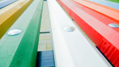 Multicolored wooden bench seat with metal bolts closeupの写真素材