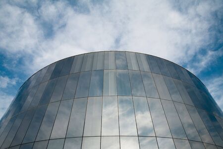 Glass round building with cloudy sky reflecting.の写真素材