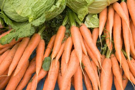 Fresh carrots and lettuces on a market stall.