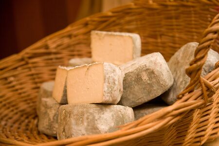 Cheeses in a cane basket on a market stall. Shallow DOF.の写真素材