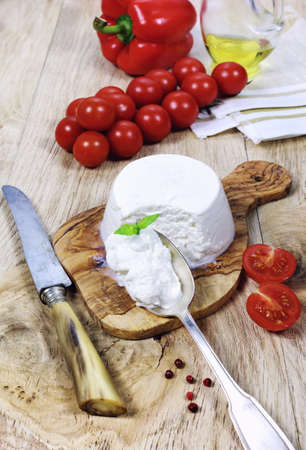 Ricotta cheese cherry tomatoes and red peppers on a wooden surfaceの写真素材