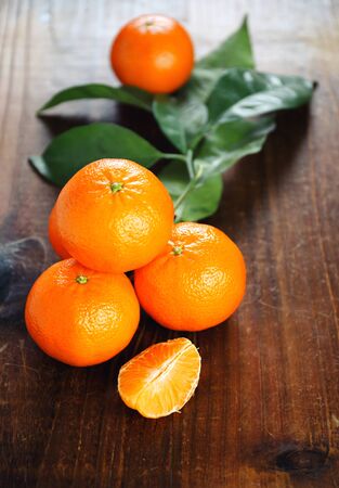 Ripe tangerines with leaves on a wooden tableの写真素材