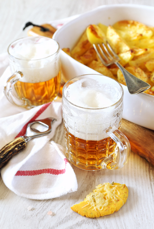 Fried potatoes with spices and two mugs of beerの写真素材