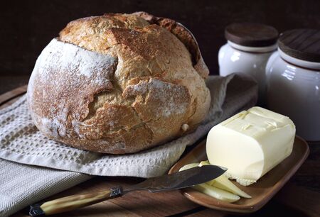French sourdough bread and butter on dark wooden chopping board